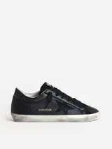 Zapatilla deportiva de piel negra con estrella de ante y refuerzo de purpurina en el talón.
