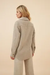 Camisa estilo leñador color beige con textura de espiga, de manga larga con puños abotonados, cuello clásico, cierre frontal con botones y dos bolsillos de parche con solapa abotonada en el pecho.