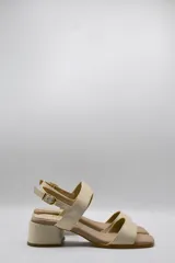 Sandalias de cuero color beige con taco cuadrado y tira ancha sobre los dedos. Presenta pulsera al tobillo con hebilla dorada.