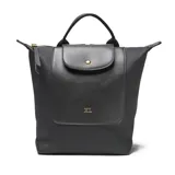 Mochila negra de material símil cuero (PU) con herrajes dorados. Presenta un asa corta superior, correas traseras regulables y un bolsillo frontal con solapa que se cierra con un broche metálico. En el centro de la solapa lleva un logo metálico con las letras "XL".