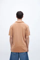 Chomba color ocre, de algodón lavado, con cuello clásico y bordado en el pecho.