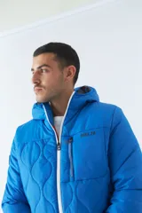 Campera de nylon azul con capucha, cierre frontal con cremallera, bolsillos laterales con cierre y logo de goma en el pecho.