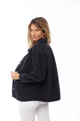 Sobrecamisa de jean color negro con cuello clásico, cierre frontal con botones metálicos, mangas largas con puños abotonados y bolsillos de parche en el pecho.
