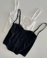 Corset negro de encaje con copas preformadas, breteles finos regulables y ballenas de soporte.