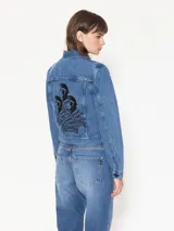 Campera de jean azul de calce estándar con bordados y parches de figuras emblemáticas del artista Edgardo Giménez.