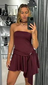 Vestido corto strapless color bordó, con falda drapeada y detalle de lazo lateral.