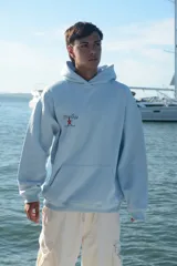 Sudadera gris con capucha, presenta estampado gráfico en la parte trasera con una estrella roja y texto relacionado.