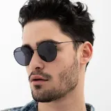 Lentes de sol INVU modelo IB12515B, con montura redonda negra y lentes polarizadas grises.