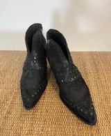 Botines negros de cuero con puntera fina y tachas plateadas. Cierre lateral con cremallera y tacón de bloque. Producto hecho a mano en Uruguay.