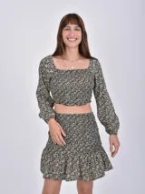 Blusa corta con estampado floral en tonos beige y negro, escote cuadrado y mangas largas abullonadas con puños elásticos.