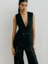 Chaleco sastrero color crema de lino, con cuello en V profundo y cierre cruzado con botón.