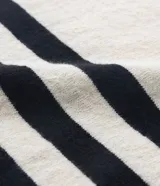 Blusa de punto liviano color crema con rayas horizontales azul marino, cuello redondo y mangas largas.