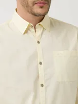 Camisa manga larga color amarillo pastel, confeccionada en popelina de algodón orgánico, con botones de madera, bolsillo en el pecho y protección UPF +20.