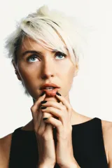 Vestido corto negro con cuello redondo y sin mangas. Presenta dos lazos blancos en la parte inferior delantera y aberturas frontales en el ruedo. Cierre trasero con cremallera metálica.