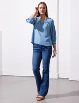 Blusa celeste de lyocell marca Zac & Rachel, con cuello a la base y escote en V con apertura central y botones. Manga ¾ con puño y botón.