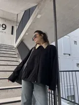 Campera negra de pana con cuello beige, cierre frontal y bolsillos laterales.