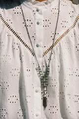 Camisa blanca de manga larga con cuello con volantes y bordados perforados. Cierre frontal con botones a tono.