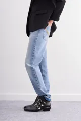 Bota de caña corta de cuero negro con tres tiras cruzadas decoradas con remaches, hebillas y puntera metálica. Tiene cierre lateral y taco ancho de 4 cm con vira metálica.