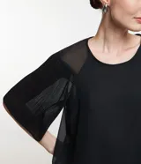 Blusa de gasa negra con cuello redondo y mangas cortas amplias texturizadas con transparencias.