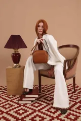 Bandolera de cuero sintético color beige, con diseño compacto y elegante. Cuenta con un bolsillo frontal con cierre y un compartimento principal con cierre. La correa es regulable.