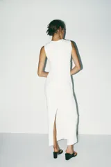 Vestido midi blanco de tejido de punto, con cuello redondo, sin mangas, drapeado en el frente, forro interior y abertura en la espalda.