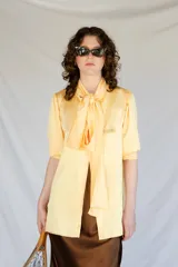 Camisa color manteca de satén con lazo en el cuello y mangas cortas.