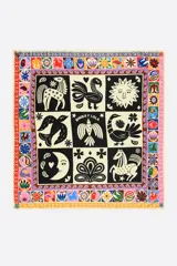 Pañuelo cuadrado de seda con estampado de motivos gráficos en blanco y negro, y borde con diseño geométrico multicolor.