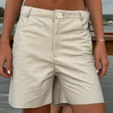 Bermuda de cuero color blanco roto o beige muy claro, con tiro alto, cierre y botón frontal, y bolsillos delanteros y traseros.