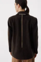 Blazer color camel de lana con solapas y cierre con botones. Presenta detalle de pespuntes blancos en los bordes.