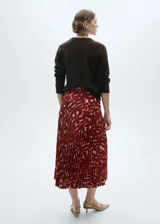 Falda midi plisada de tejido fluido con estampado abstracto en tonos rojo y beige.