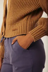 Cárdigan color marrón con tejido de punto acanalado, escote en V, cierre frontal con botones y mangas largas abullonadas.