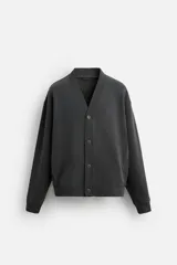 Cárdigan gris oscuro de tejido de mezcla de algodón con interior perchado, corte holgado, cuello pico, manga larga, bolsillos de vivo en la cadera, acabados en rib y cierre frontal de botonadura.