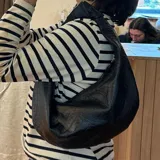 Cartera tipo hobo de cuero sintético negro con textura de cocodrilo.