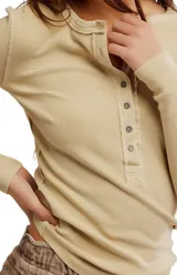 Camiseta tipo henley de manga larga, color blanco, confeccionada en algodón elástico con cuello redondo y tapeta de botones.