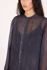 Vestido camisero largo midi de calce recto, confeccionado en tejido liviano y semitransparente de color azul oscuro. Presenta cierre frontal con botones, cuello mao, mangas largas con puño y terminaciones irregulares en el bajo.