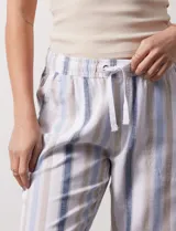 Pantalón de lino estampado a rayas verticales azules y blancas, marca DASH. Tiene pretina ancha elastizada con lazo ajustable.