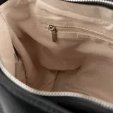 Cartera negra de cuero sintético graneado, con doble asa de mano y correa bandolera regulable. Tiene cierre superior, bolsillo interno con cierre y bolsillo interno abierto.