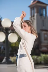 Saco largo color crudo, con cuello redondo, bolsillos frontales con apliques de cuero plateado y mangas largas.