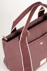 Cartera en símil cuero tramado, con asas fijas centrales y correa regulable, incluye un bolsillo externo y un gran compartimento interior con cierre adicional.