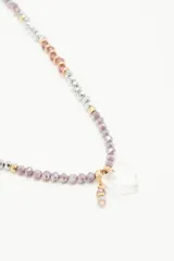 Collar corto de cuentas plateadas, lilas y marrones con dije transparente en forma de corazón.