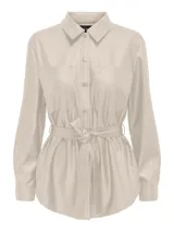Camisa color beige de eco cuero con cuello clásico, cierre frontal con botones a presión, mangas largas con puños abotonados, dos bolsillos de parche en el pecho y cinturón de lazo en la cintura.