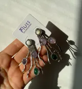 Aros colgantes de alpaca plateada con diseño de ramitas y piedras de colores: blanco, lila y verde.