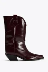 Bota de cuero color bordó, estilo cowboy, con punta fina, tiradores laterales y tacón bajo.