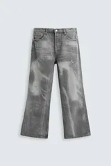 Pantalón de jean gris de corte flare, con cinco bolsillos, lavado con efecto de contraste en las piernas y bajo con acabado irregular.