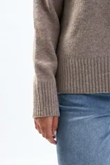 Suéter de tejido de punto color beige, con cuello redondo y manga larga. Presenta un calce relajado y puños y ruedo acanalados.