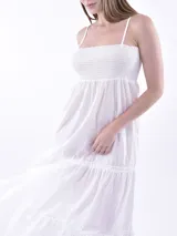 Vestido largo blanco de verano con tirantes finos ajustables y corpiño fruncido (smock). La falda es de corte amplio con volados en capas.