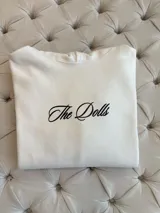 Hoodie negro de corte oversize, con capucha, bolsillo frontal y estampado blanco en la espalda con la inscripción "The Dolls The Dolls VIP CLUB".