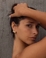 Aros pequeños de bronce con forma irregular y acabado liso, estilo huggie o argolla gruesa.