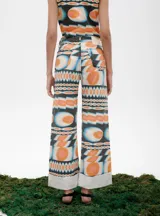 Pantalón de jean azul oscuro con corte acampanado, tiro medio y dobladillo en el ruedo. Presenta costuras marcadas en el frente y estampado abstracto en tonos grises y blancos en el interior del dobladillo.