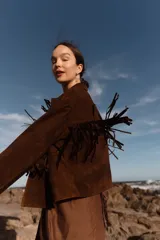 Chaqueta marrón de cuero gamuzado con flecos en la parte delantera y trasera.